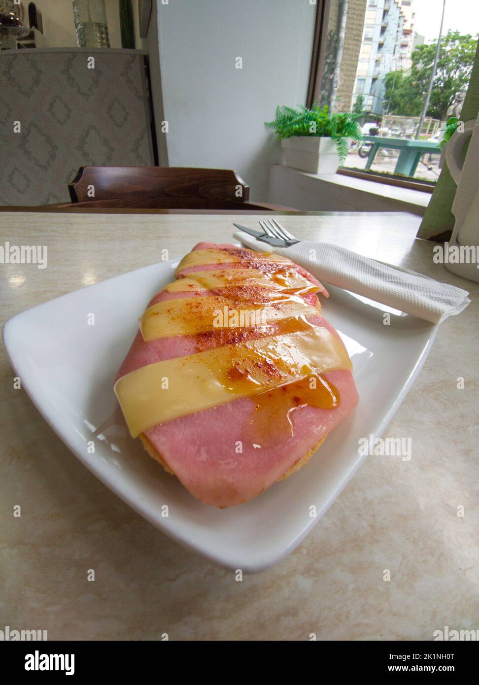 Pain grillé au jambon avec tranches de fromage saupoudrées de Pimenton de la Vera. Couteau et fourchette enveloppés dans une serviette en papier Banque D'Images