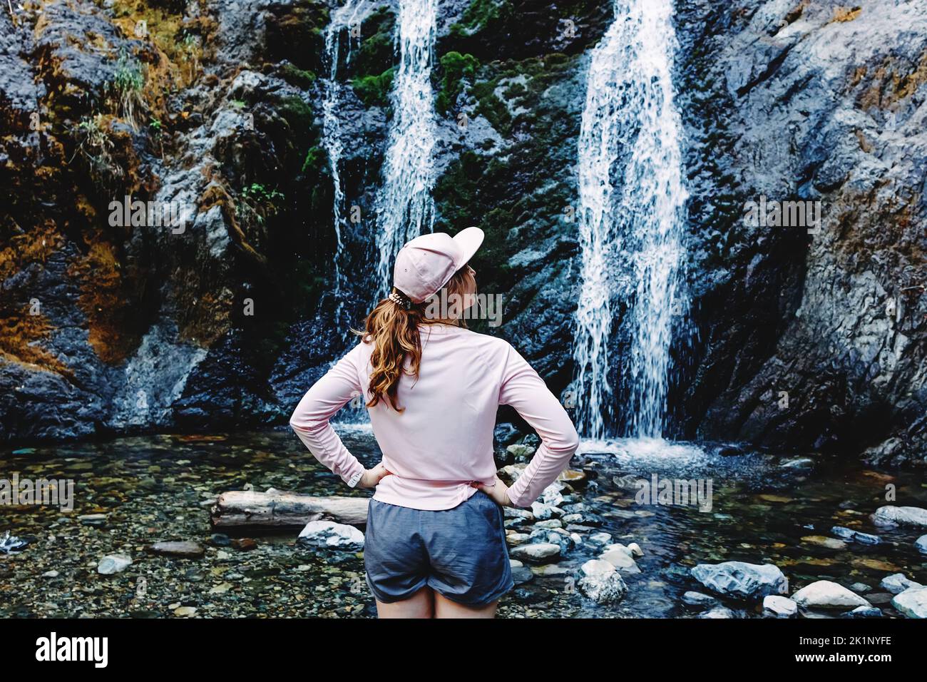 Jeune femme qui profite du temps près de la chute d'eau après la randonnée, vue de l'arrière Banque D'Images