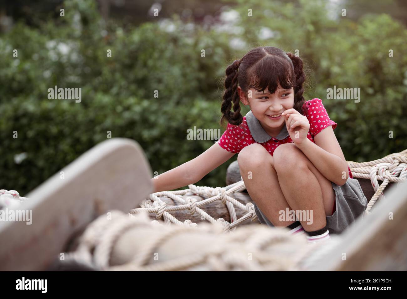 Bonne fille jouant sur une corde raide dans une aire de jeux. Banque D'Images