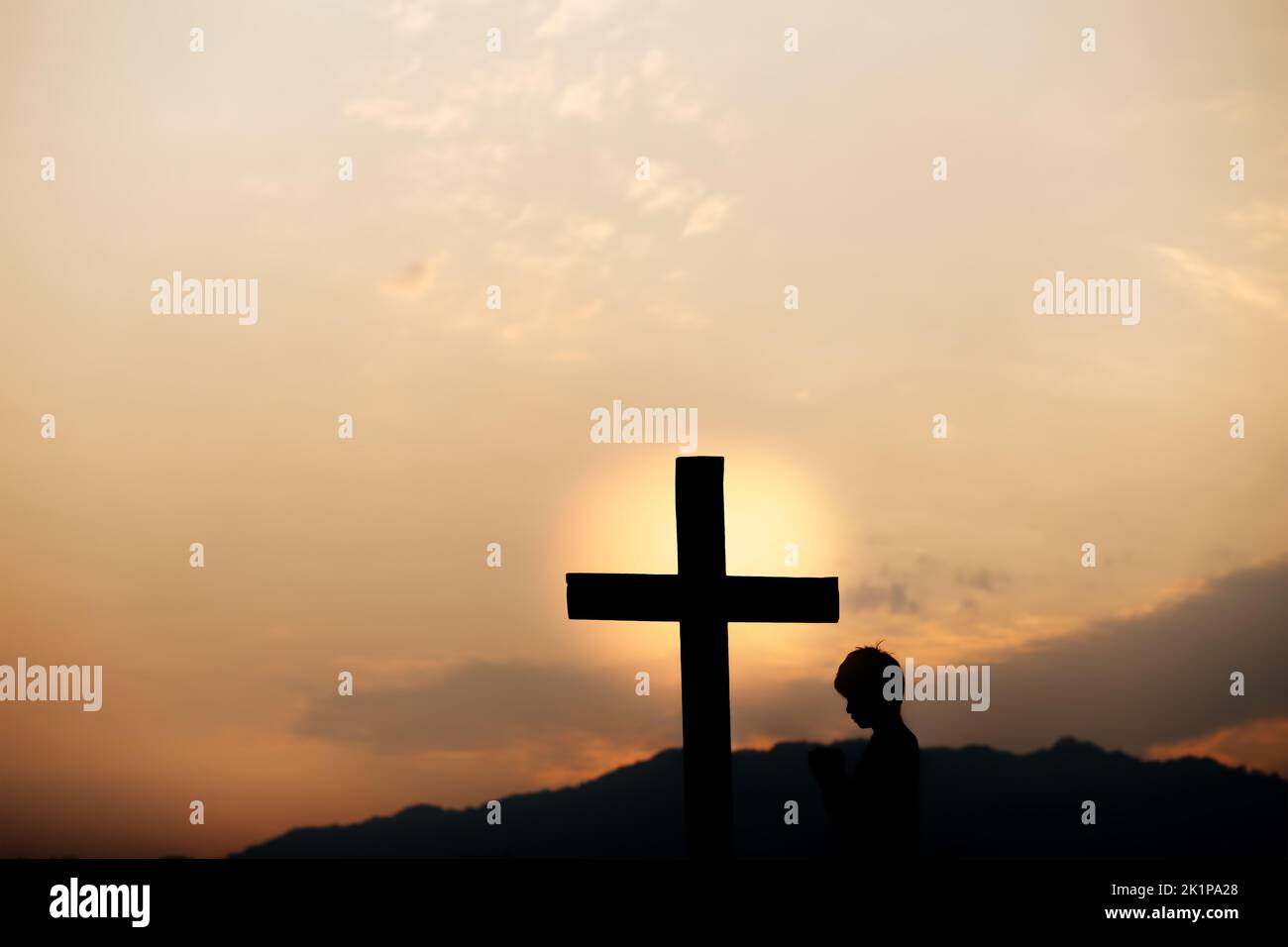 Silhouette of a man prayer in front of cross on mountain at sunset. concept of religion. Banque D'Images