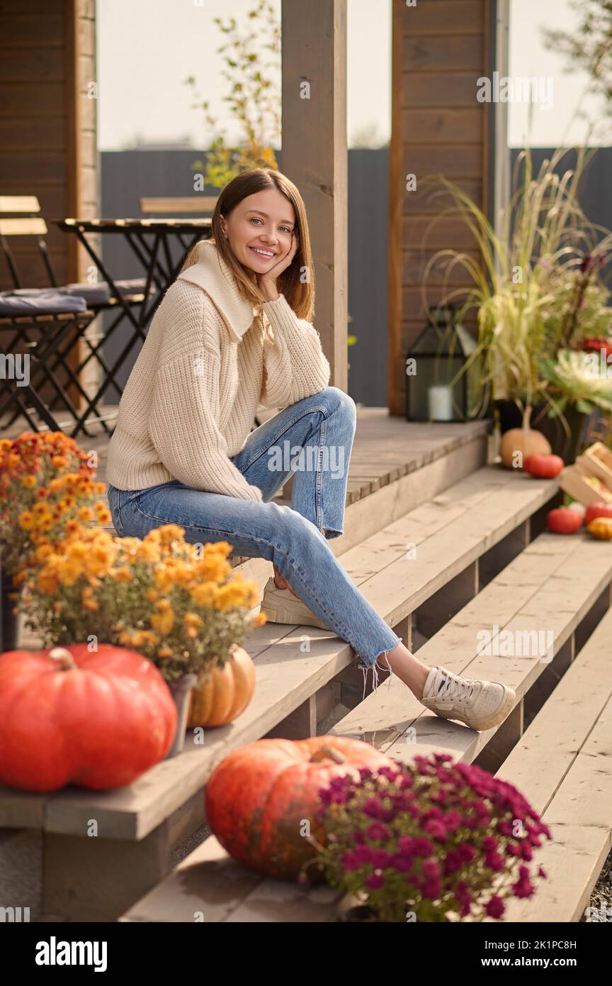 Femme gaie assise sur le porche du cottage en bois Banque D'Images