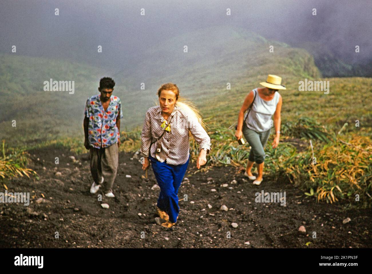Guide et deux femmes touristes grimpant sur le sentier escarpé le volcan de la Soufrière, St Vincent, Iles du vent, Antilles, 1962 Banque D'Images