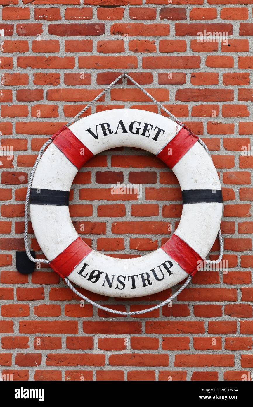 Vieille bouée de sauvetage suspendue sur un mur de briques à Lonstrup, Danemark Banque D'Images