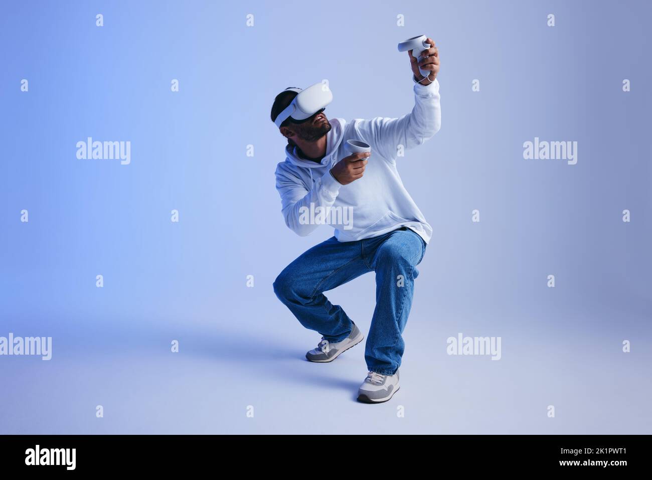 Joueur explorant des jeux vidéo de réalité virtuelle dans un studio. Un jeune homme jouant avec des lunettes de réalité virtuelle et des contrôleurs. Jeune homme actif expérience Banque D'Images