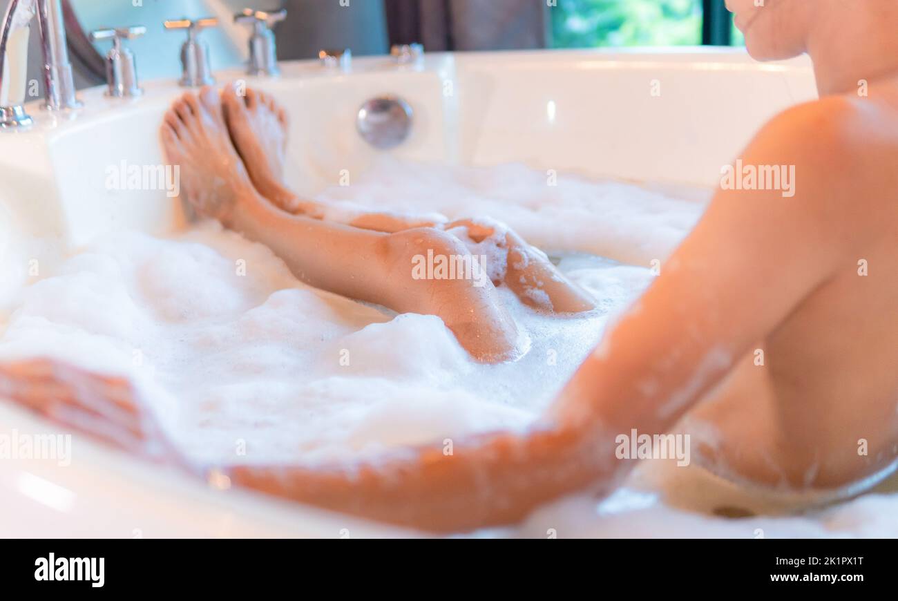 Femme jambes dans la baignoire avec mousse, appréciant dans l'hôtel spa Banque D'Images