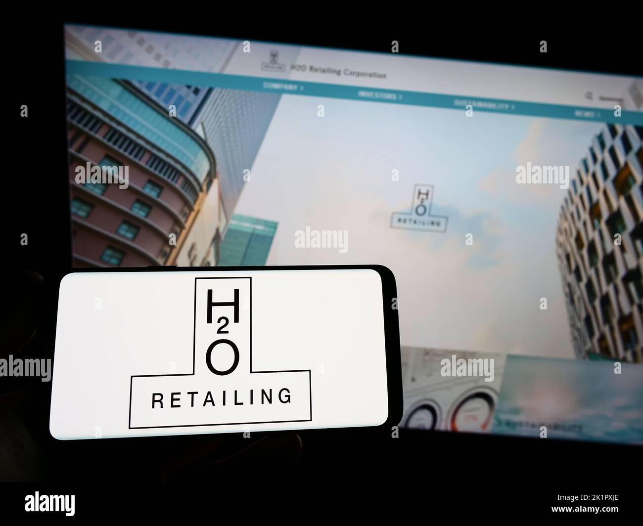 Personne tenant un smartphone avec le logo de la société japonaise H2O Retailing Corporation à l'écran devant le site Web. Mise au point sur l'affichage du téléphone. Banque D'Images