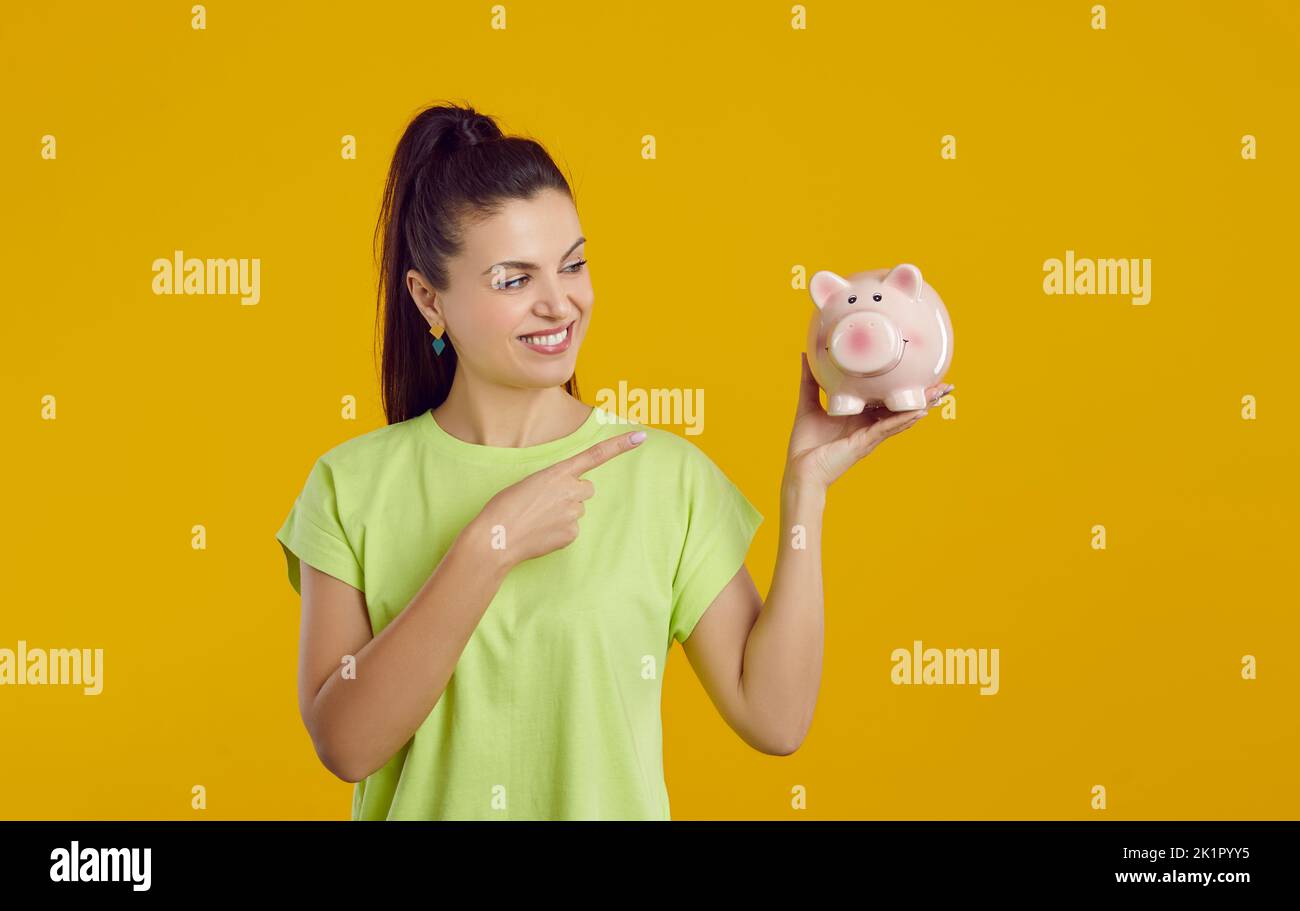 Une femme souriante montre une banque de pigeons dans sa main, faisant allusion à une offre favorable de la banque. Banque D'Images