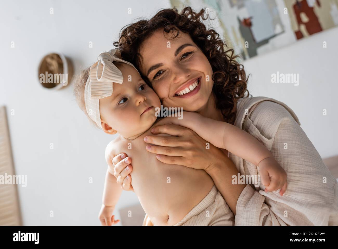 une mère en forme de couvre-lit en souriant tout en embrassant une petite fille dans un serre-tête, image de stock Banque D'Images