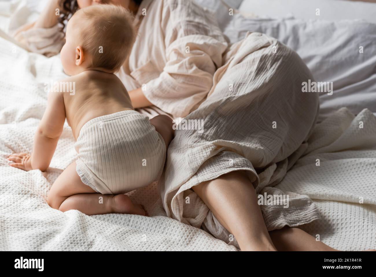vue rognée de la mère dans les vêtements de détente couchés près de la fille de bébé sur le lit, image de stock Banque D'Images