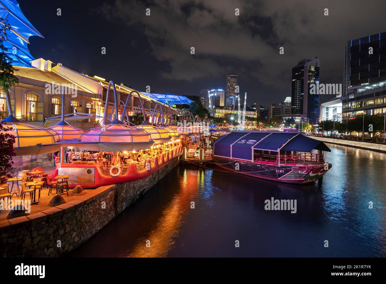 Clarke Quay sur la rivière Singapour illuminé par des lumières colorées avec vie nocturne et bumboats fournissant des croisières sur la rivière. Clarke Quay Singapour Banque D'Images