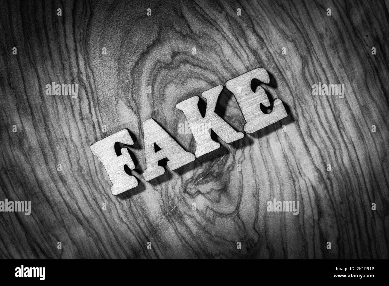 Mot « Fake » - Inscription par des lettres en bois gros plan. Image en noir et blanc Banque D'Images