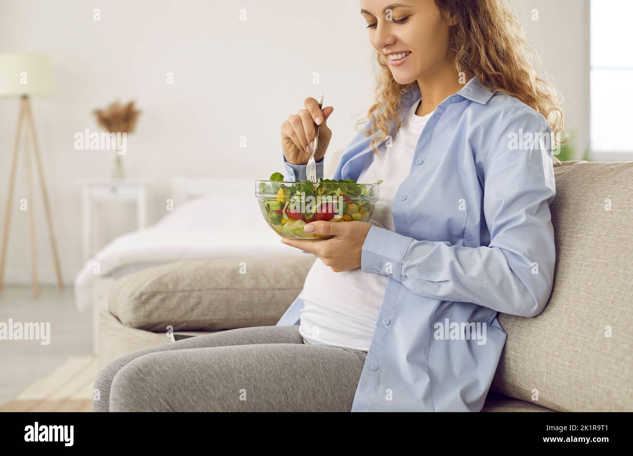 Une jeune femme heureuse mange une salade végétarienne saine Banque D'Images