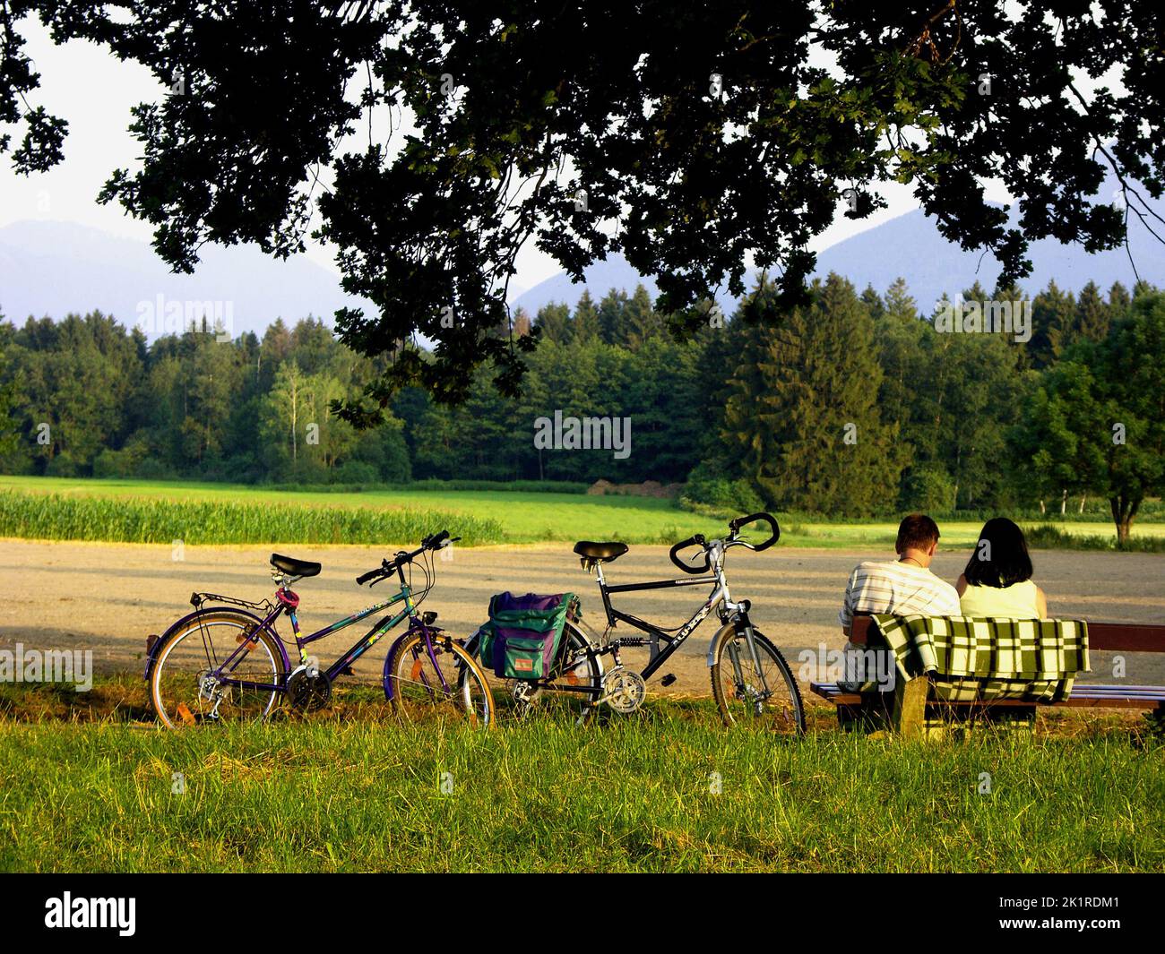 Couple sur banquette assise, avec vélo à côté, Chiemgau, haute-Bavière, Allemagne Banque D'Images