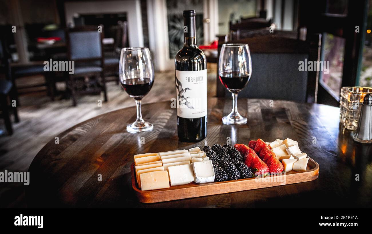 Composition alimentaire avec vin, fromage et fruits sur un plateau en bois avec des verres à vin rouge fourrés Banque D'Images