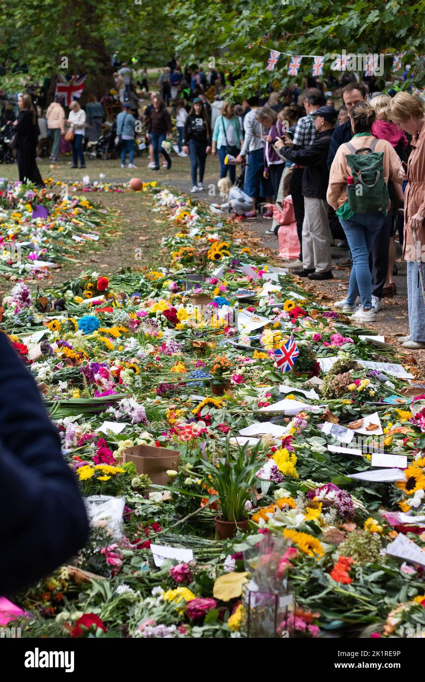 Un groupe de personnes autour des fleurs sur le sol pendant les préparatifs funéraires de la reine Elisabeth II Banque D'Images