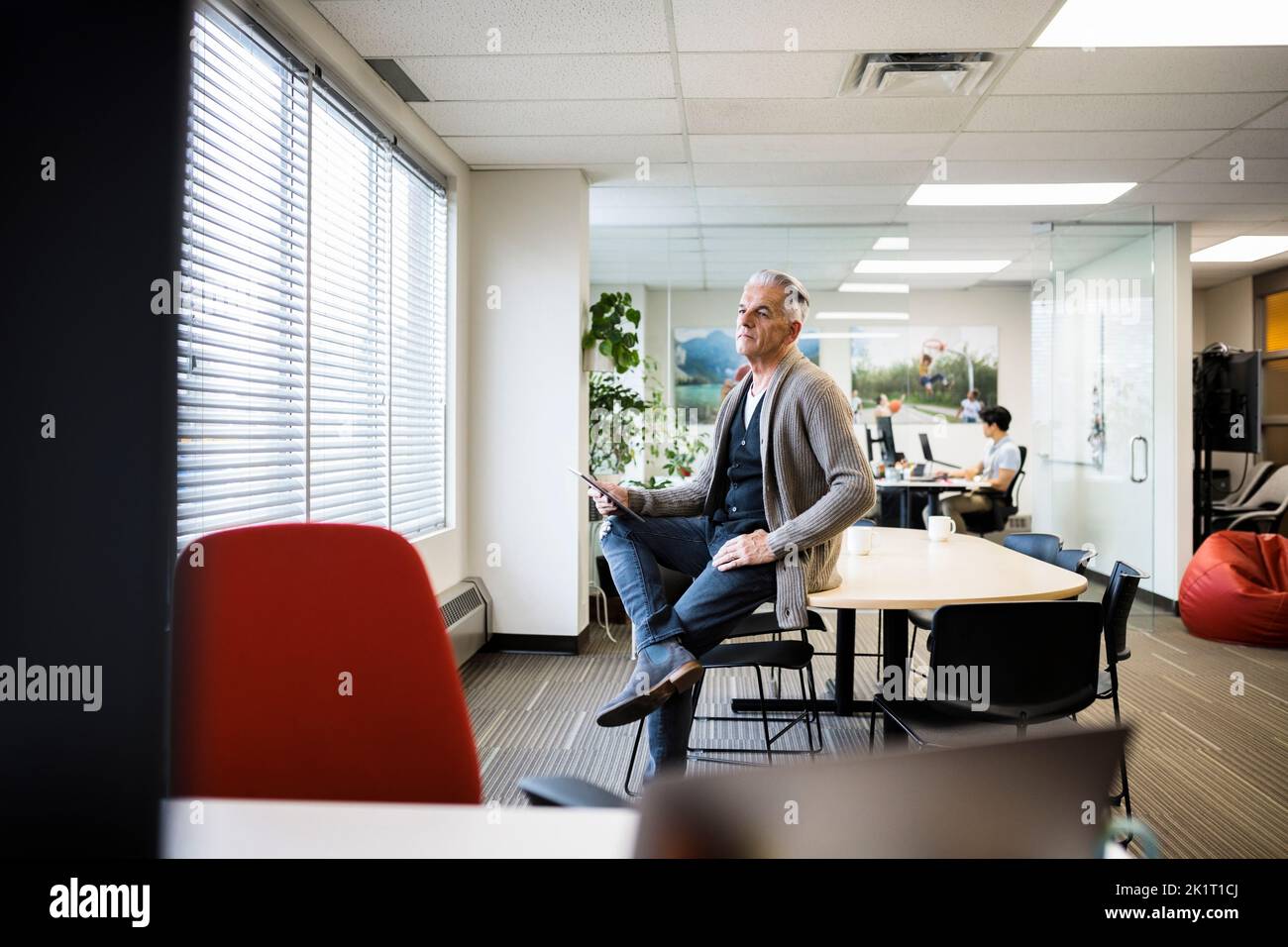 Homme d'affaires senior utilisant une tablette numérique dans un bureau ouvert Banque D'Images