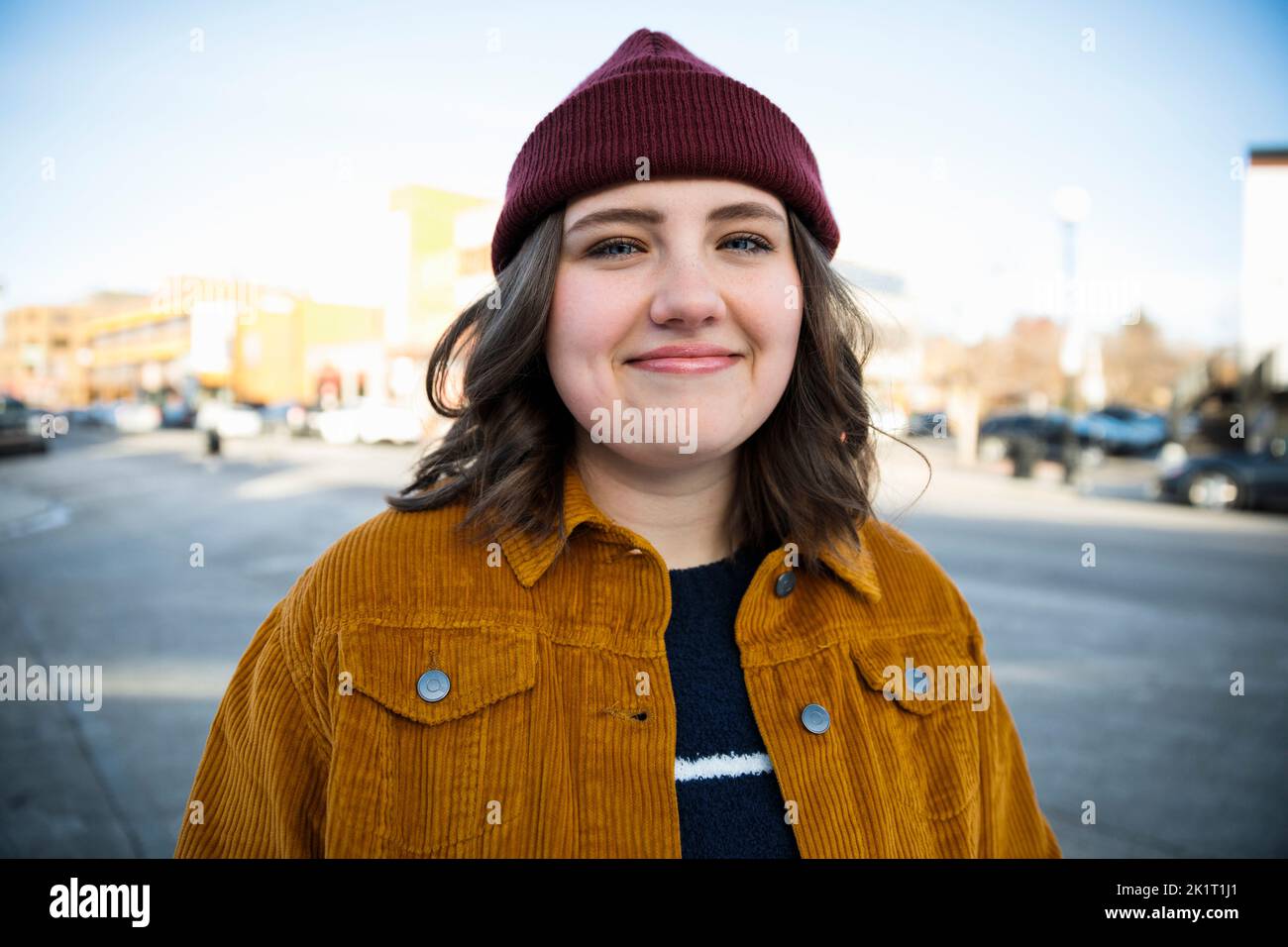 Portrait confiante, jeune femme souriante dans la rue de la ville Banque D'Images