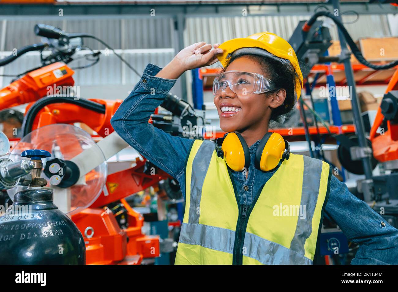 Jeune femme ingénieuse africaine travaillant dans une usine robotique avancée avec sécurité Banque D'Images