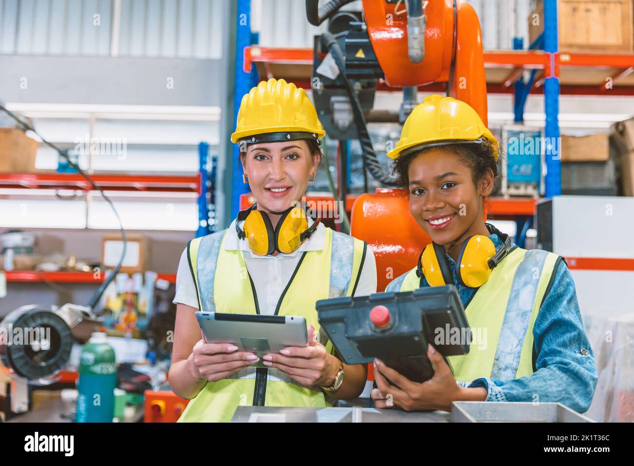 Les femmes travaillent ensemble pour former des équipes de travail au travail dans une usine moderne de machines de soudage robotisées avancées. Banque D'Images