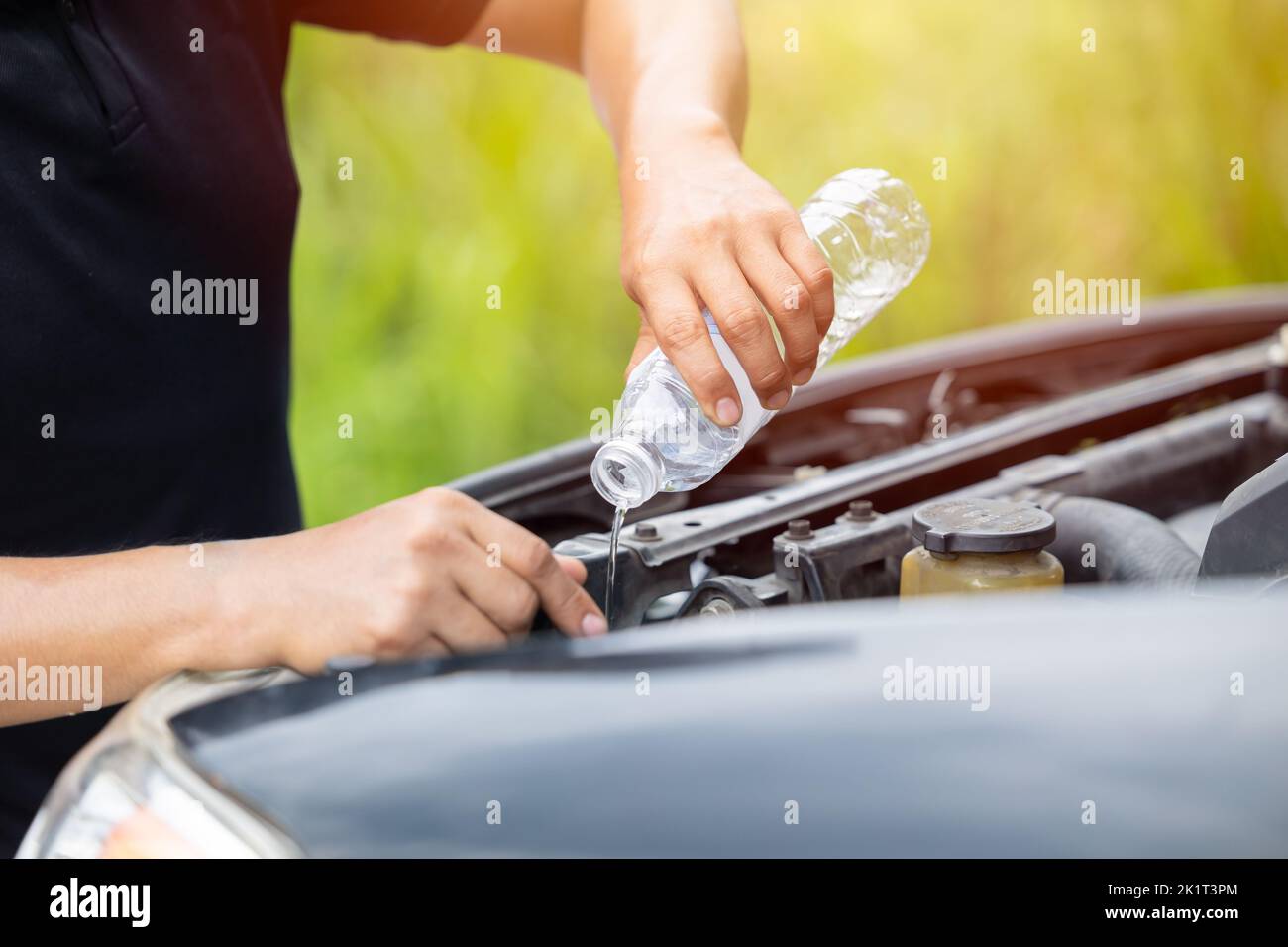 homme eau distribuant à la main remplissage du radiateur de voiture avec du liquide de refroidissement concentré ou de l'eau distillée pour moteur froid en été Banque D'Images