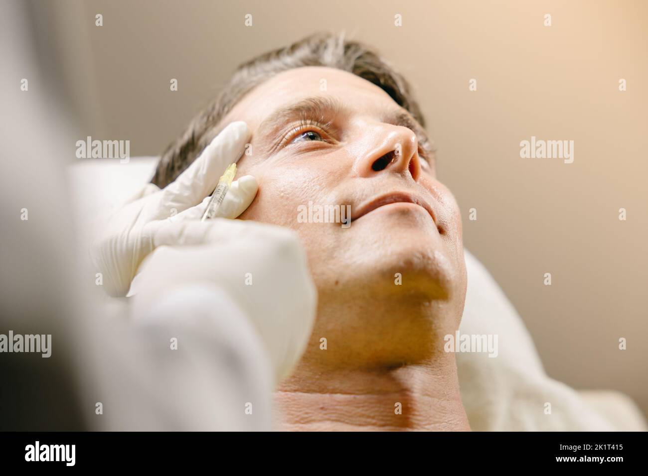 Les rides faciales mâles éliminent le processus par injection de toxine Botulinum élévation du visage en clinique avec la main du médecin Banque D'Images