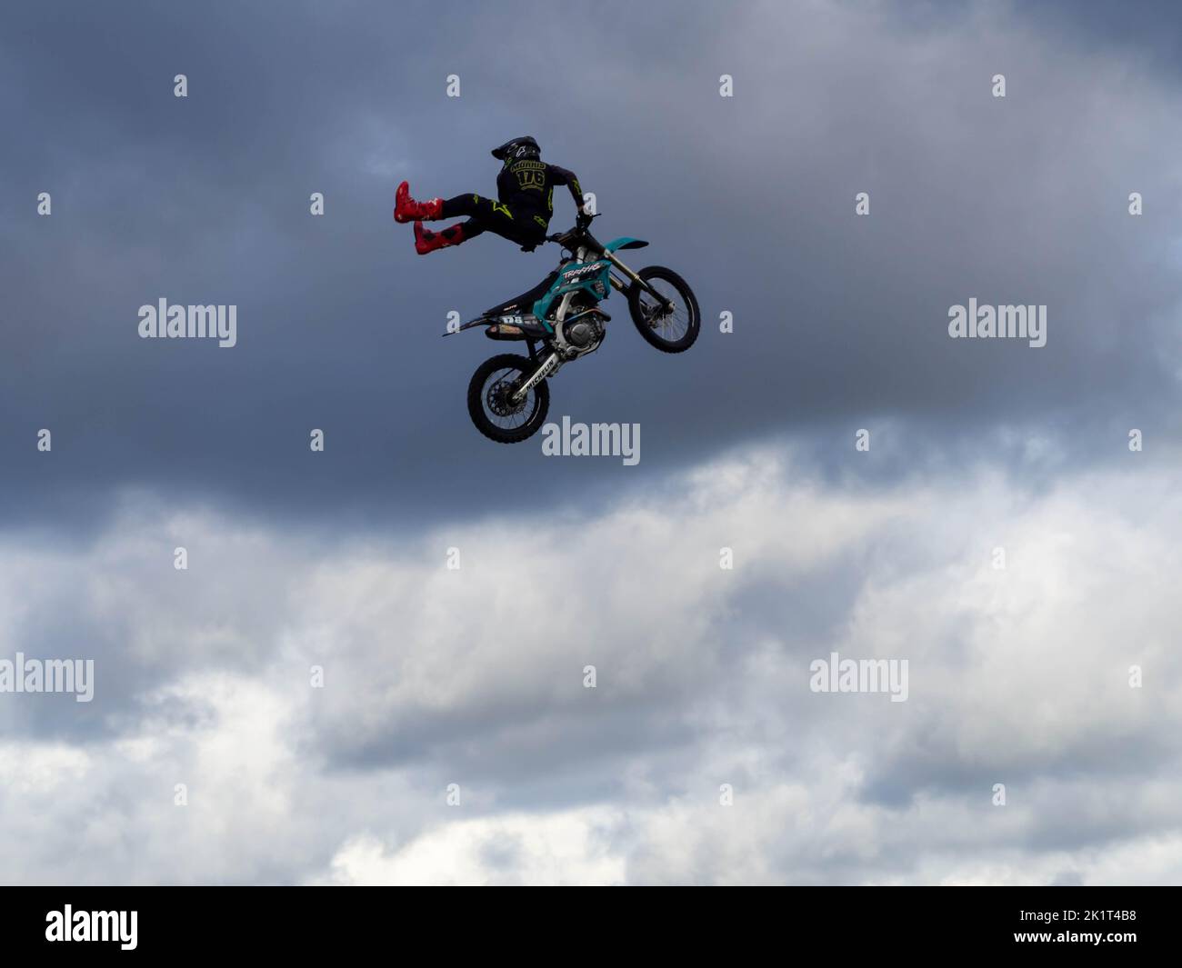 Le pilote FMX Stunt de Broke a fait une posture de cascadeur élevée à l'arrière d'une moto, dans les nuages lors d'une journée automnale fraîche au Truckfest NW. Banque D'Images