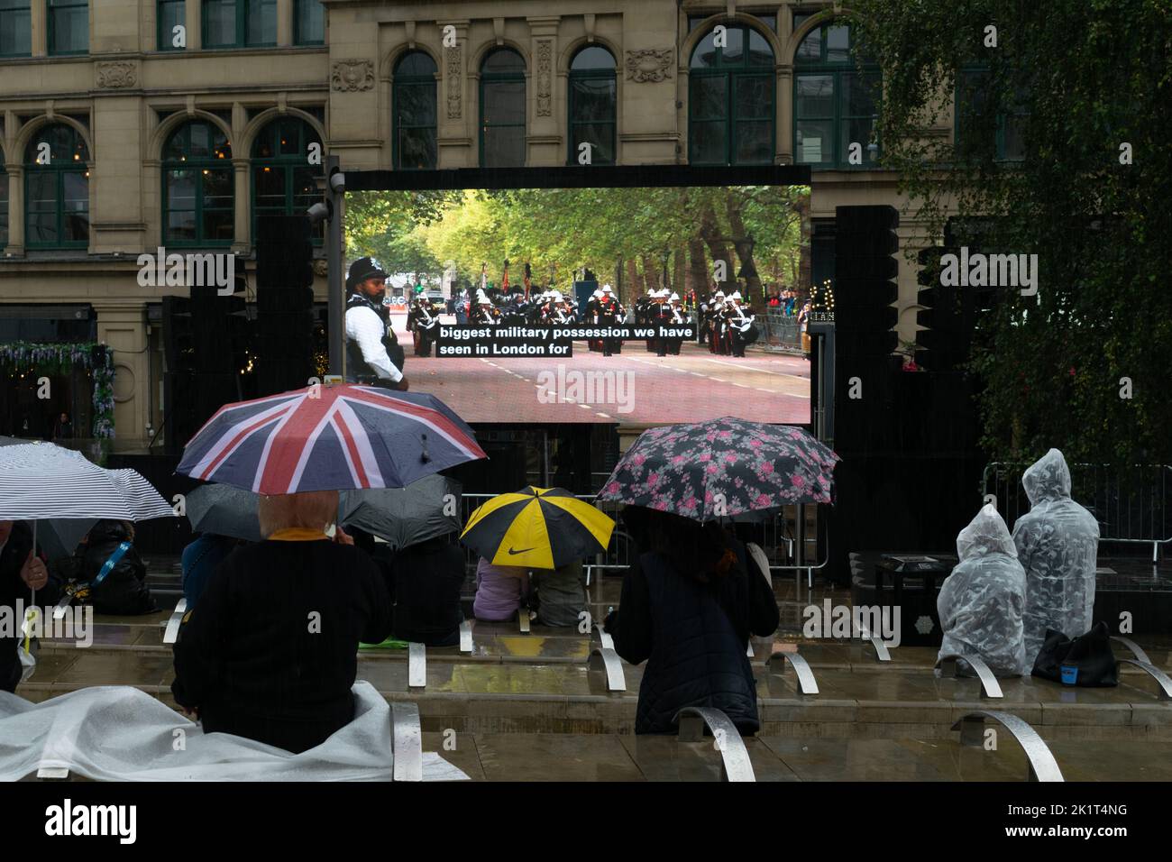 Écran d'affichage électronique dans le carré d'échange montrant les funérailles du monarque Queen Elizabeth II Les gens regardent sous la pluie avec un parapluie Union Jack. Banque D'Images