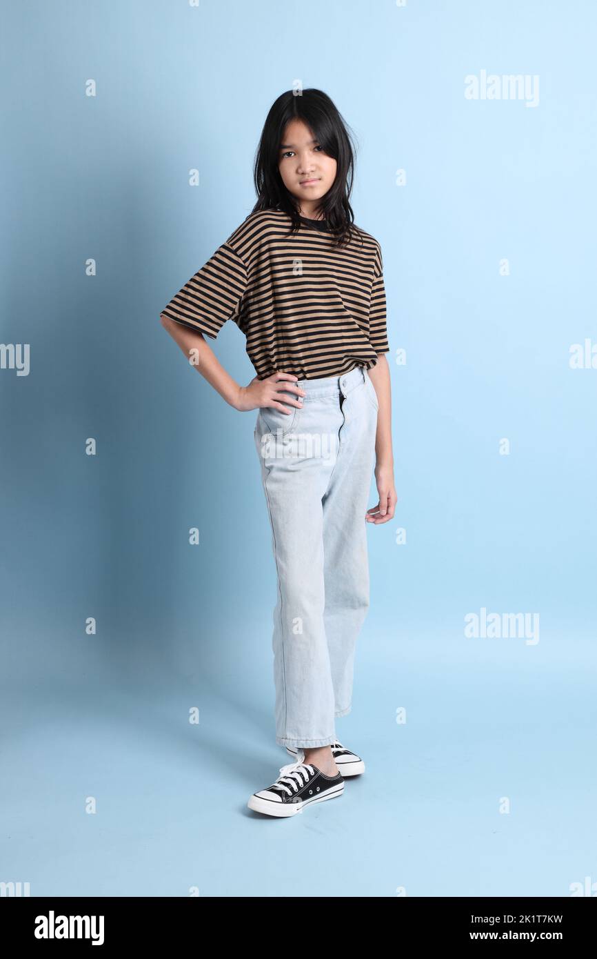 La jeune fille asiatique avec chemise marron sur fond bleu. Banque D'Images