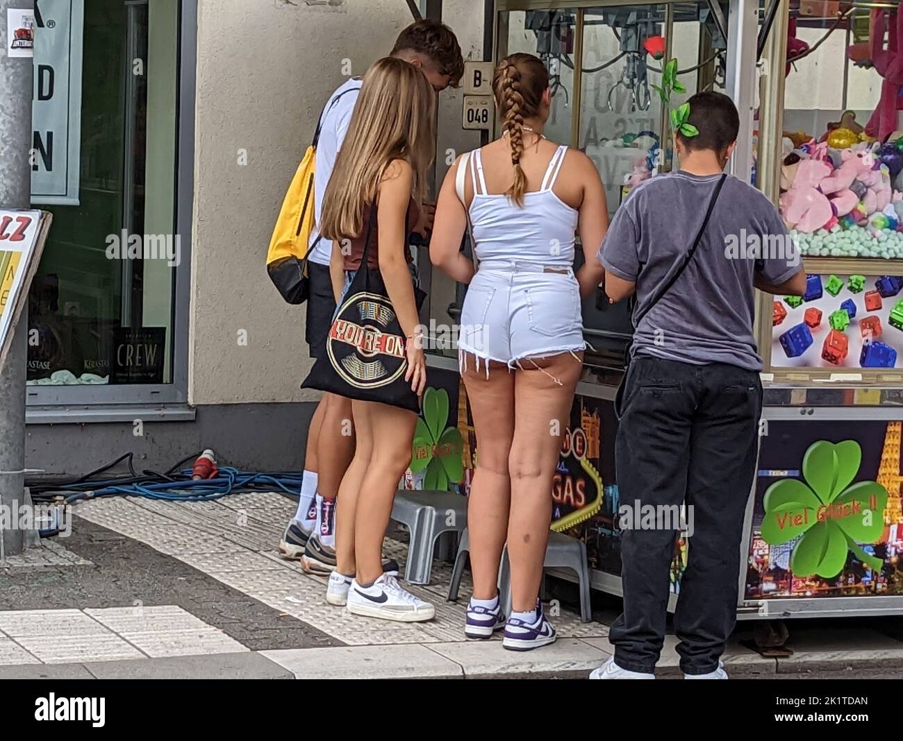 Un groupe de jeunes se tiennent sur un stand de jeu avec des jouets en peluche Banque D'Images