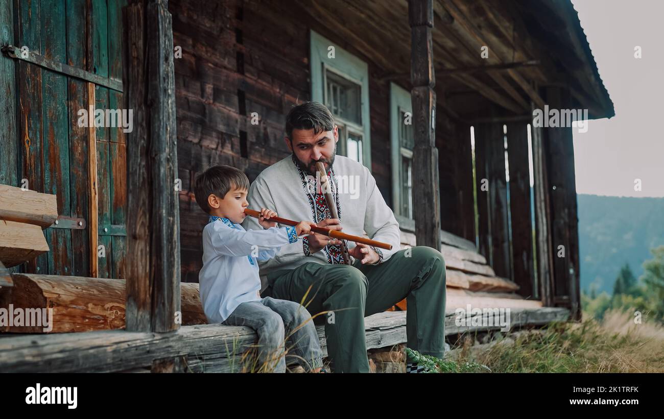 Petit garçon avec papa jouant sur des flûtes en bois de vent - sopilka ukrainien. Duet familial, concept de musique folk. Père et fils brodés traditionnels Banque D'Images