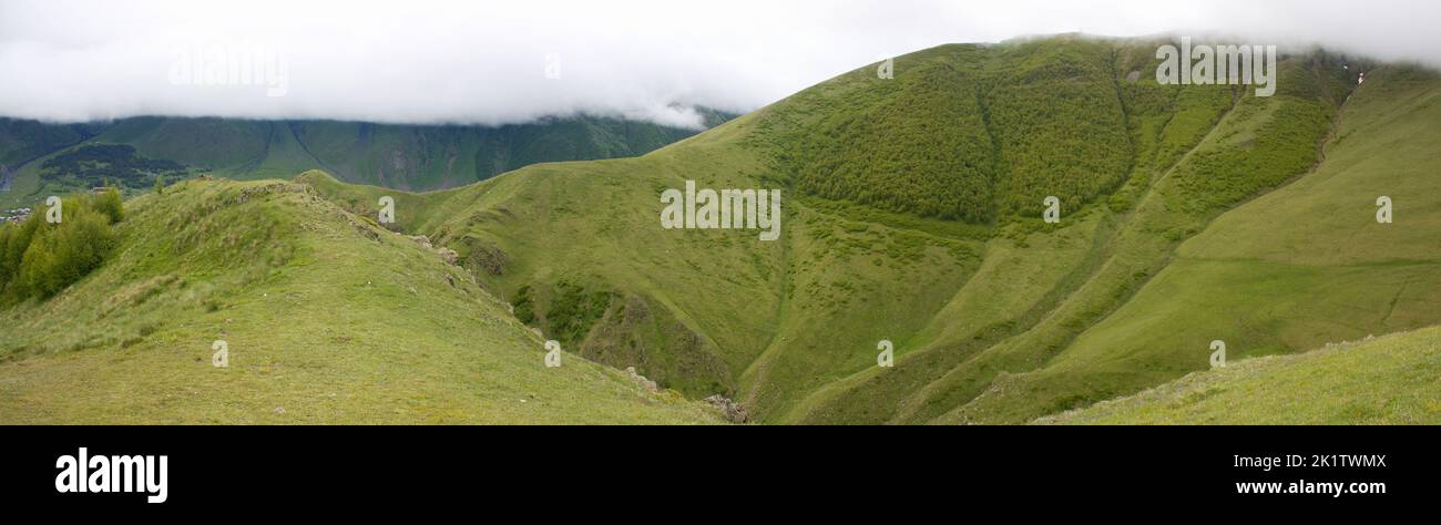Vue sur une vallée de montagne à Stepantsminda (Kazbegi) près de l'église de la Trinité de Gergeti en Géorgie (Grand Caucase) Banque D'Images