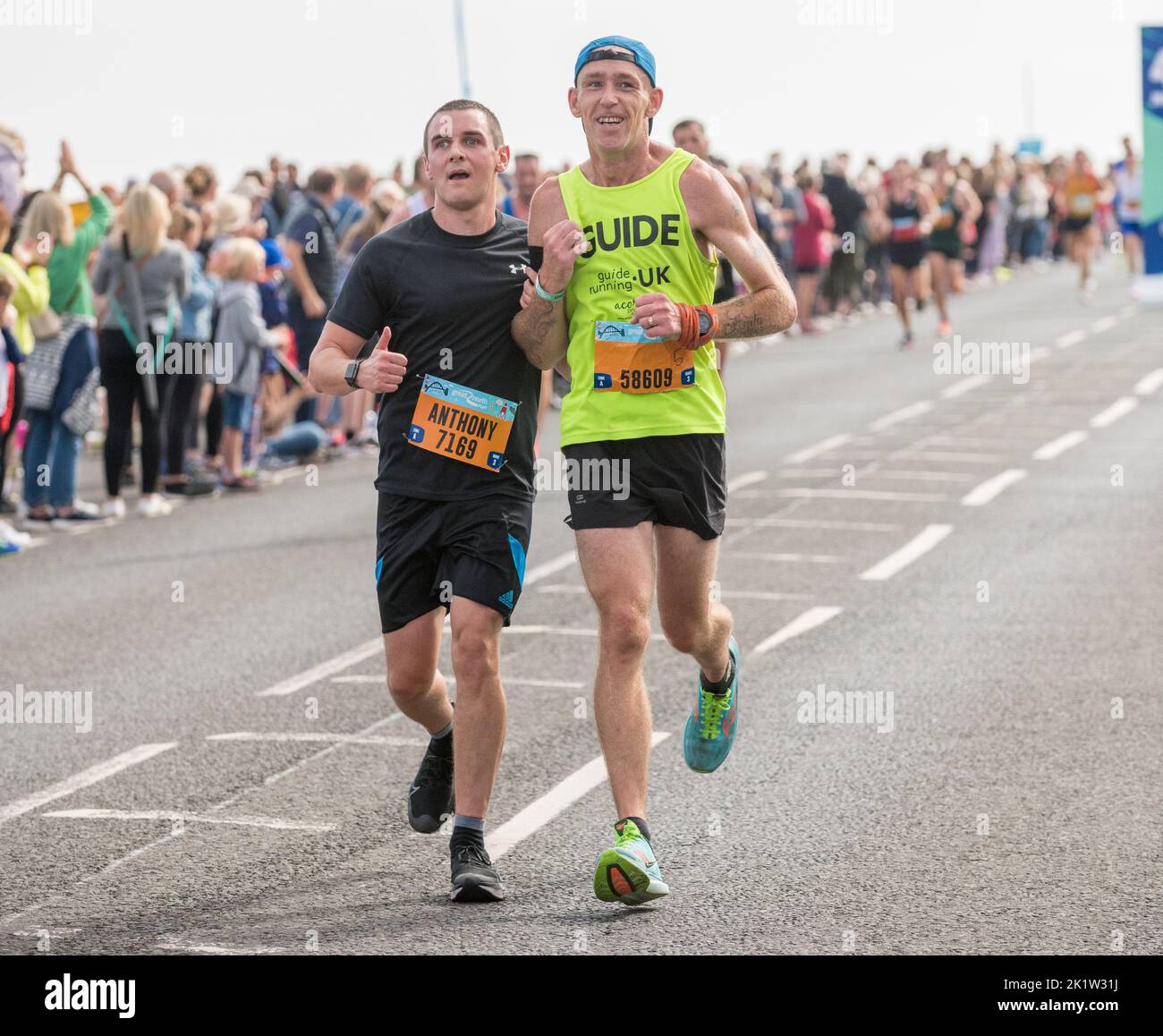 Coureur de l'organisation britannique Guide Running aide à soutenir un coureur participant au semi-marathon Great North Run 2022 Banque D'Images