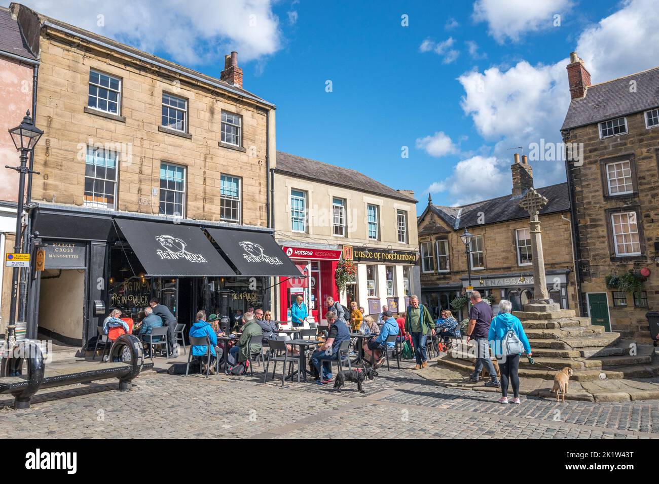 Les gens se sont assis et se sont relaxants à l'extérieur du café et restaurant Pig in Muck en après-midi de soleil dans la ville marchande de Northumberland d'Alnwick le jour du marché. Banque D'Images