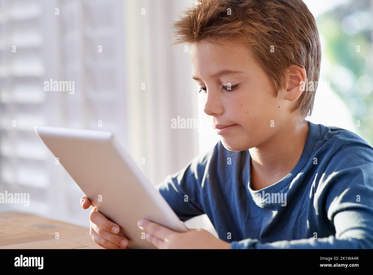 Un excellent outil d'apprentissage. Un jeune garçon utilisant une tablette numérique pour faire ses devoirs. Banque D'Images