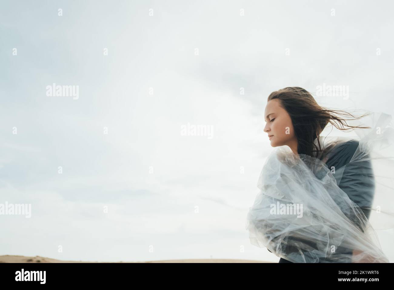 Liberté féminine. Paix intérieure. Espoir futur. Inspiration tranquillité. Portrait d'art de la femme paisible avec les yeux fermés portant le film de polyéthylène dans le froid a Banque D'Images