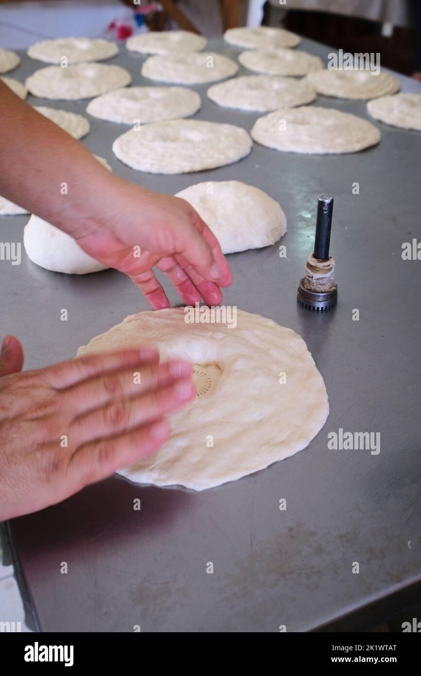 Détail de la mise en forme et de l'estampage de pâte fraîche sans pain à l'aide d'un outil chirchiq. Au marché de Chorsu, Bazar à Tachkent, Ouzbékistan. Banque D'Images
