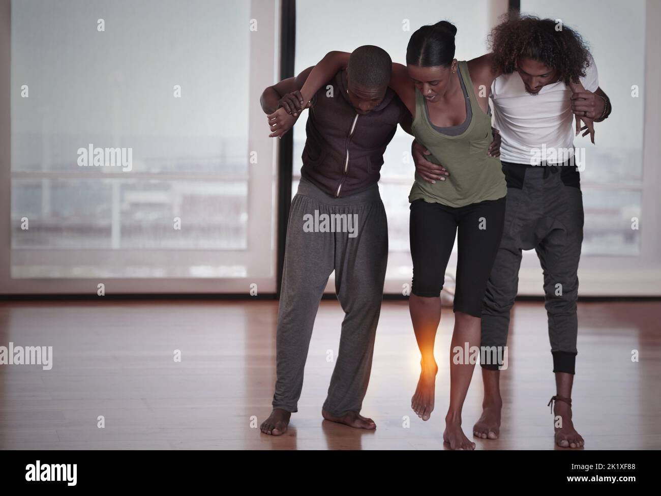 Elle l'aidant hors du studio. Deux jeunes danseurs aident une amie hors de la piste de danse avec une cheville blessée Banque D'Images