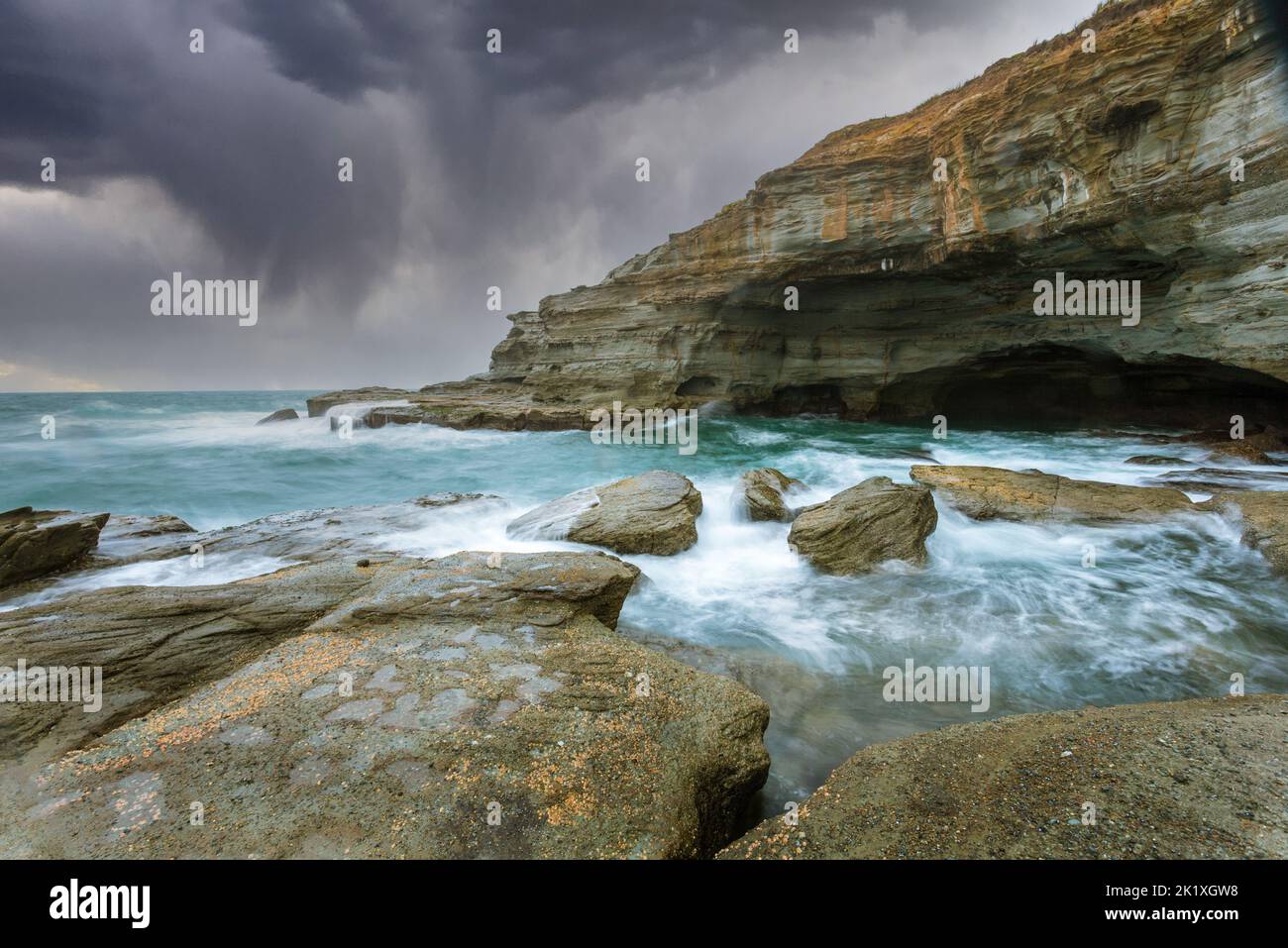 La plage de grès fait des grottes en Australie un matin de tempête avec des mers agitées Banque D'Images