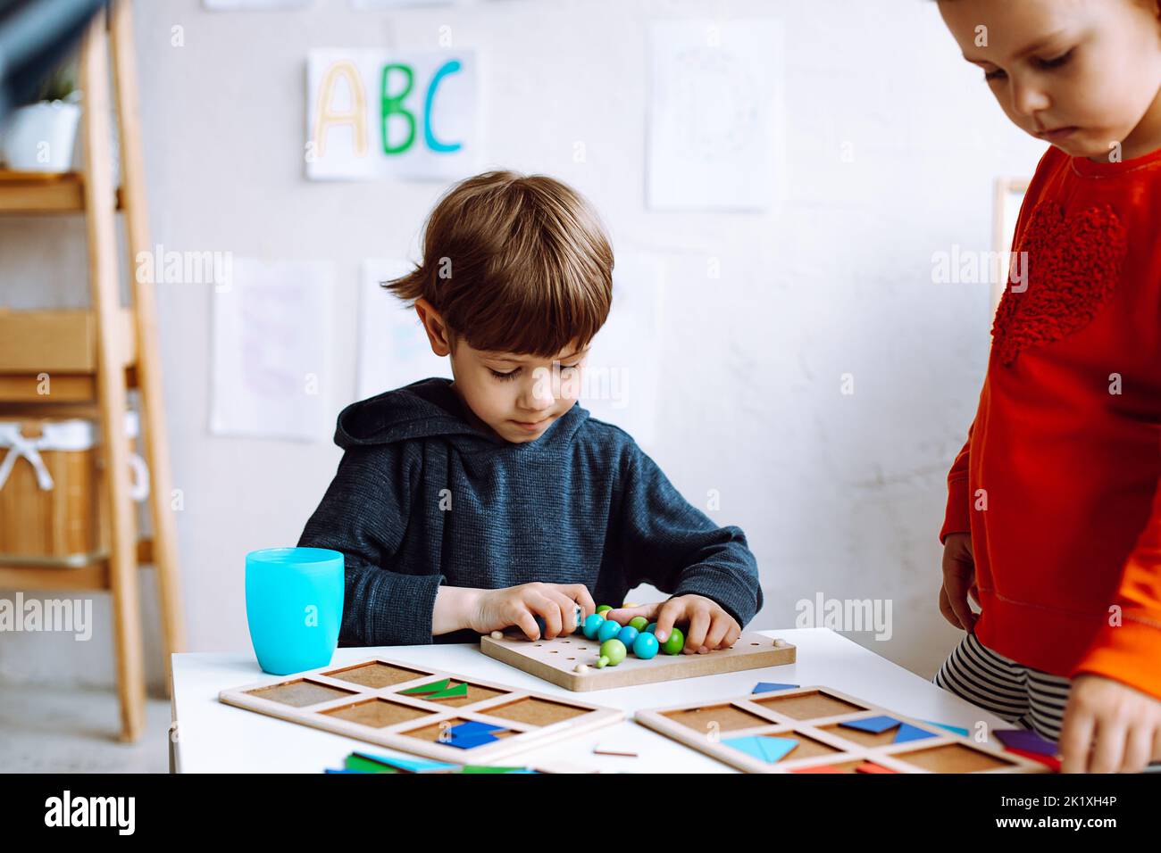 Mignon, adorable petit garçon et fille faisant l'exercice logique intelligent avec des figures comme jeu de jouet dans le groupe de classe. Cours pour enfants en cadeau Banque D'Images