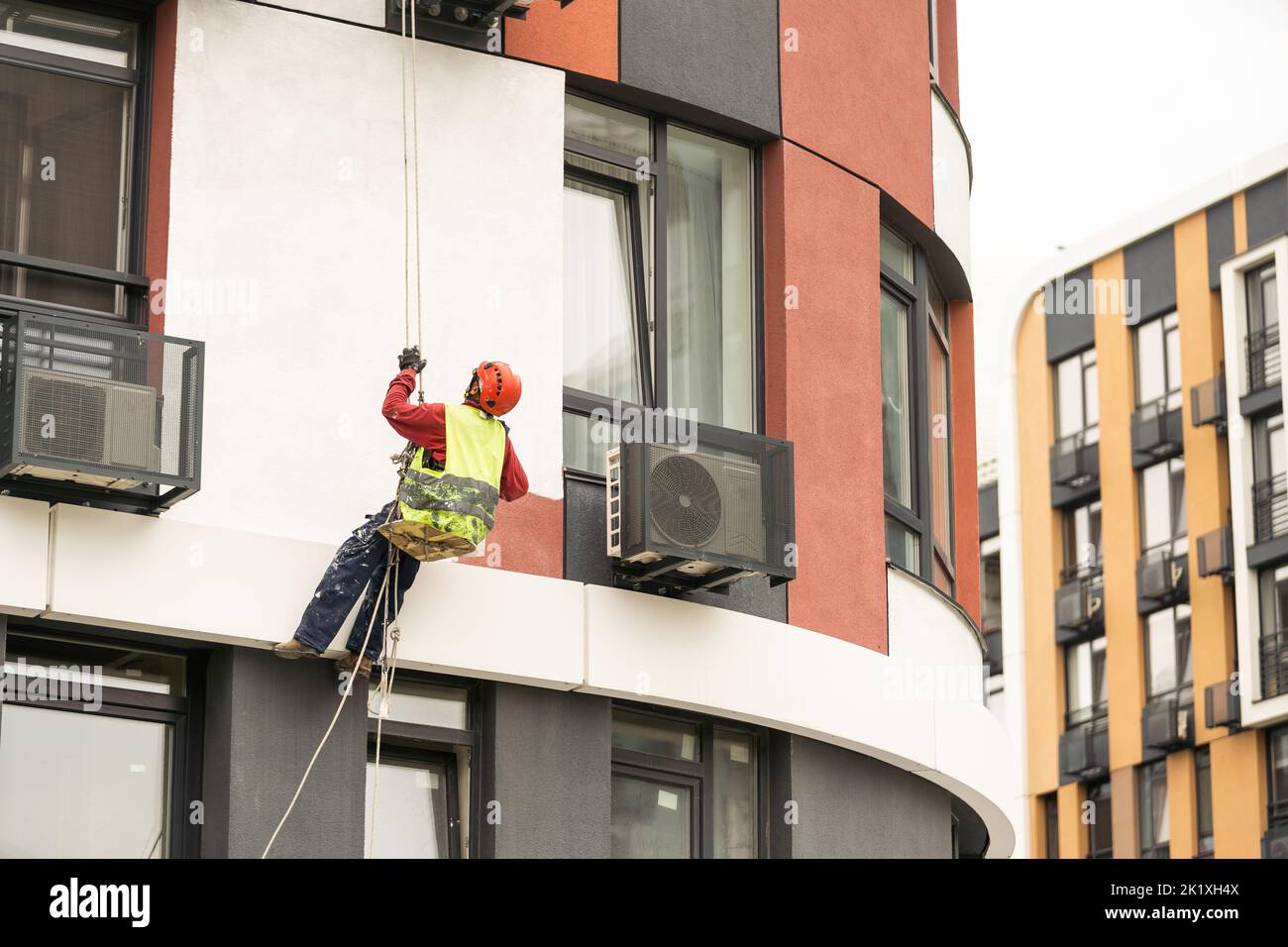 Les peintres-altitude modernisent la façade du bâtiment. Banque D'Images