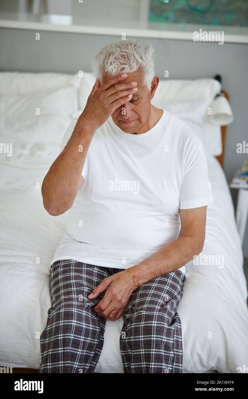 C'est tellement déprimant... un homme âgé qui a l'air découragé en étant assis sur son lit dans un établissement de vie assistée Banque D'Images
