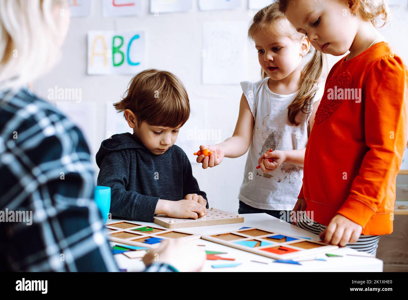 Mignon, adorable petit garçon et deux filles aider à faire l'exercice logique avec des figures et des formes dans le groupe de classe. Éducation précoce Banque D'Images