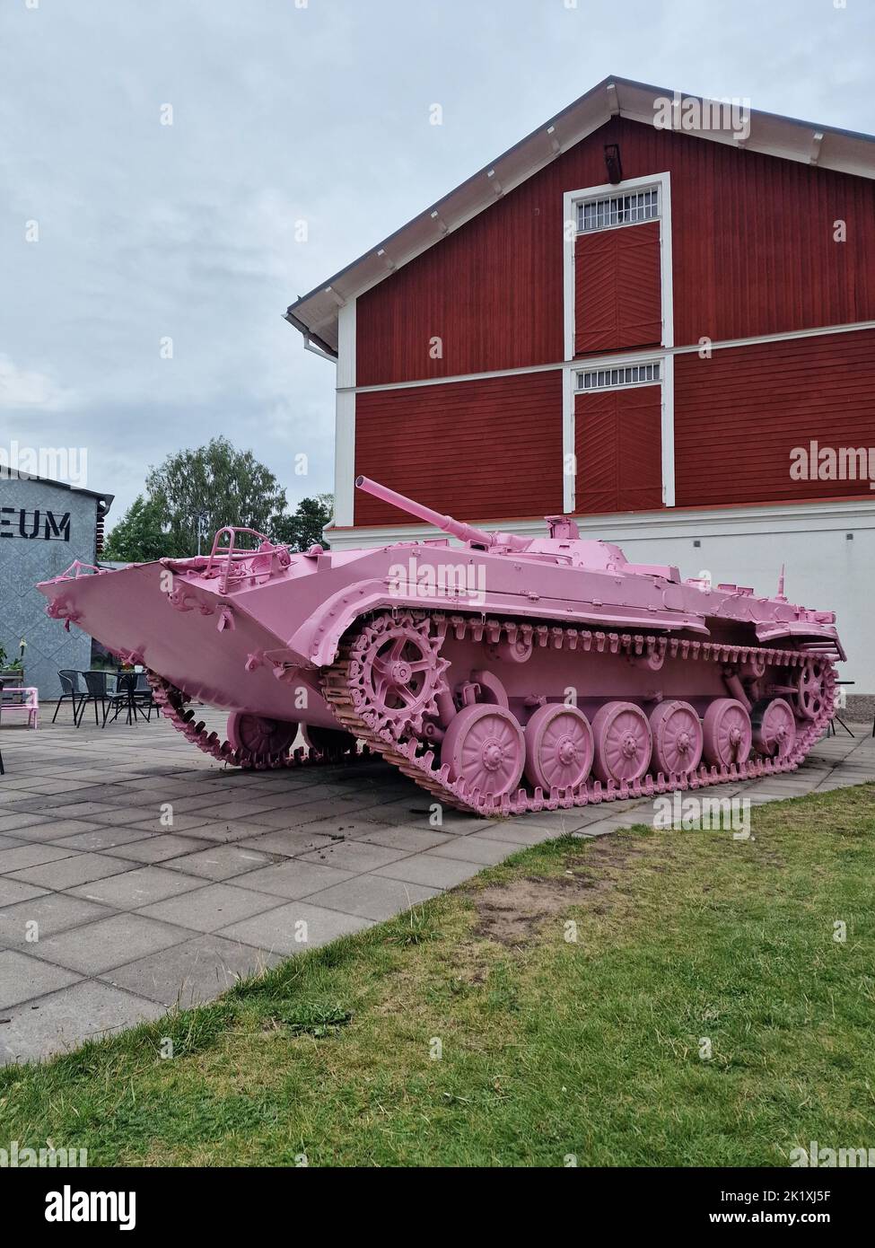 Une photo verticale d'un parc d'armes à feu d'assaut StuG III rose à côté d'un bâtiment rouge Banque D'Images