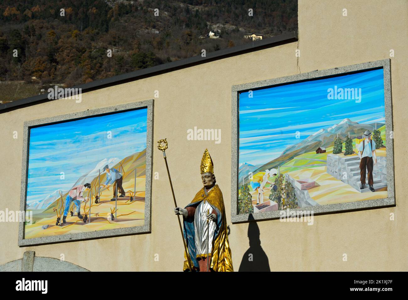 Statue de Saint-Théodul, patron des vignerons, devant des peintures avec des scènes de viticulture à l'ancienne abbaye de Vetroz, Vetroz, Valais, Suisse Banque D'Images