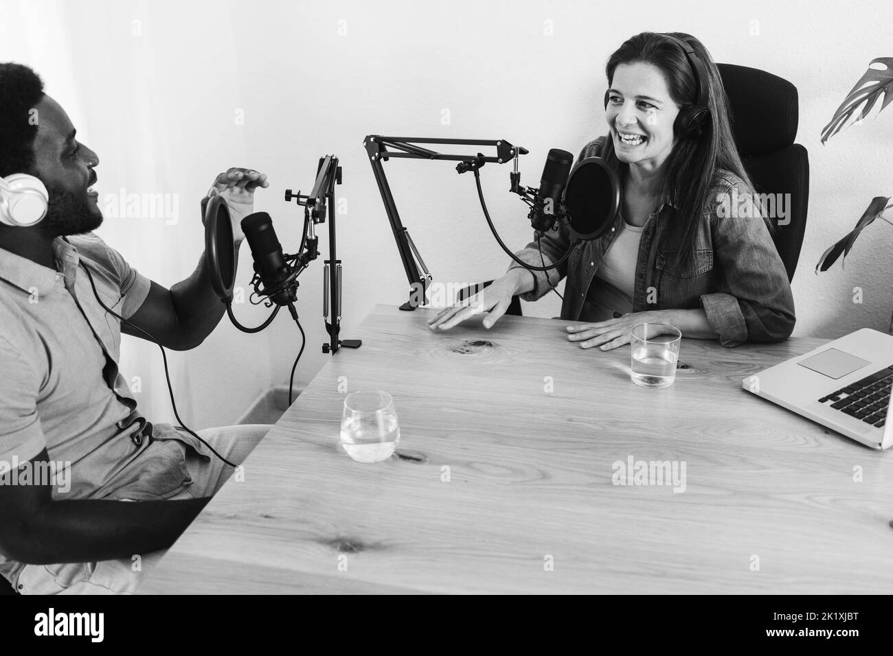 Balado en streaming multiracial dans un studio numérique - Focus sur le microphone de la femme - montage noir et blanc Banque D'Images