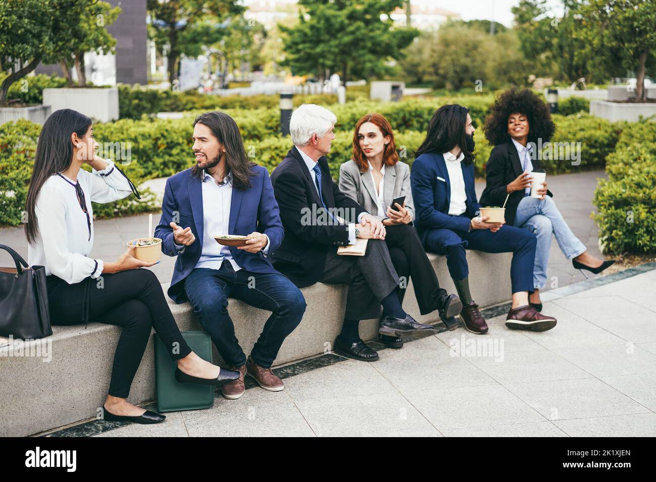 Les femmes d'affaires multiethniques font une pause déjeuner à l'extérieur de l'immeuble de bureaux - Focus sur le visage de l'homme gauche Banque D'Images