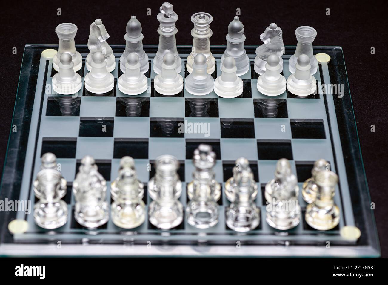 Ensemble de pièces d'échecs en verre transparent sur noir, mise au point sélective, espace de copie Banque D'Images