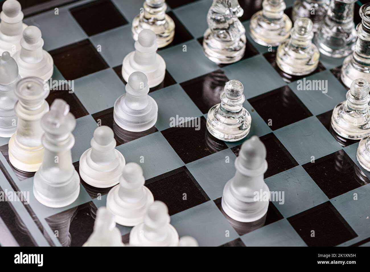 verre transparent, pièces d'échecs transparentes sur un damier, mise au point sélective, gros plan, isolé sur le noir Banque D'Images