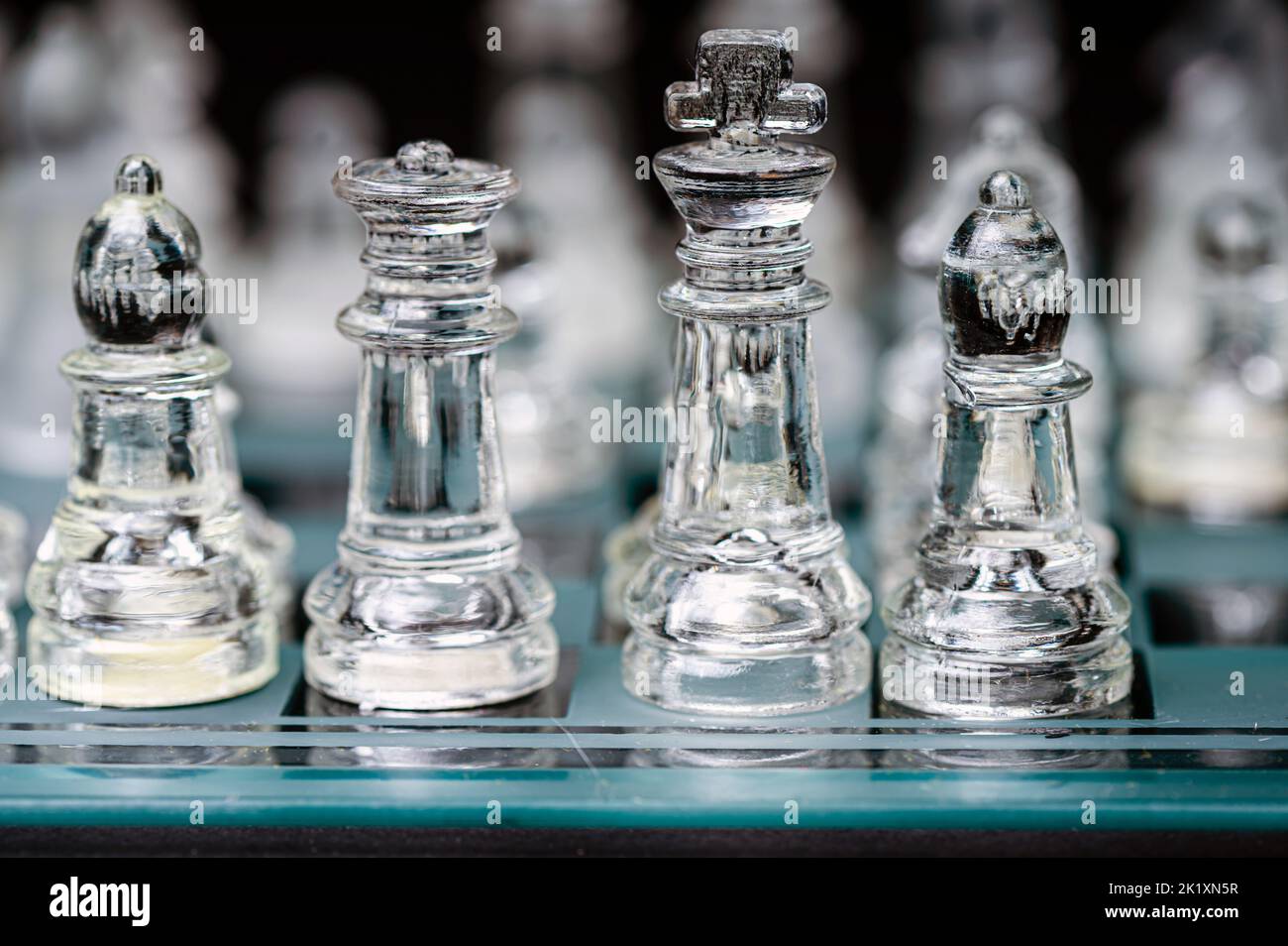 verre transparent, pièces d'échecs transparentes sur un damier, mise au point sélective, gros plan, isolé sur le noir Banque D'Images