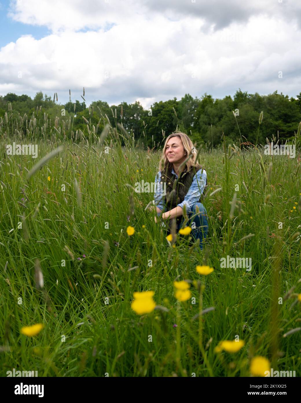 Femme se relaxant dans la prairie parmi les fleurs et les herbes. Banque D'Images